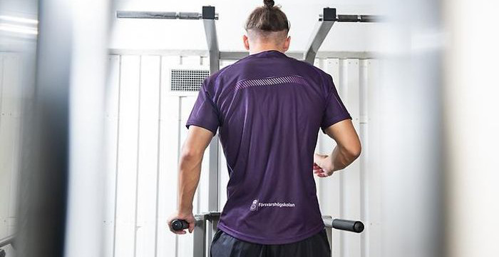 Ryggtavla av man i träningsmaskin.