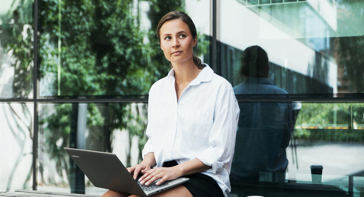 Female student with laptop outside the SEDU building.