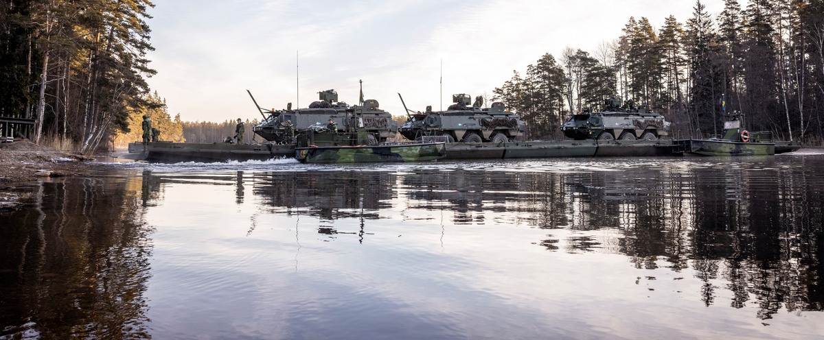Tanks crossing a river in a forest.