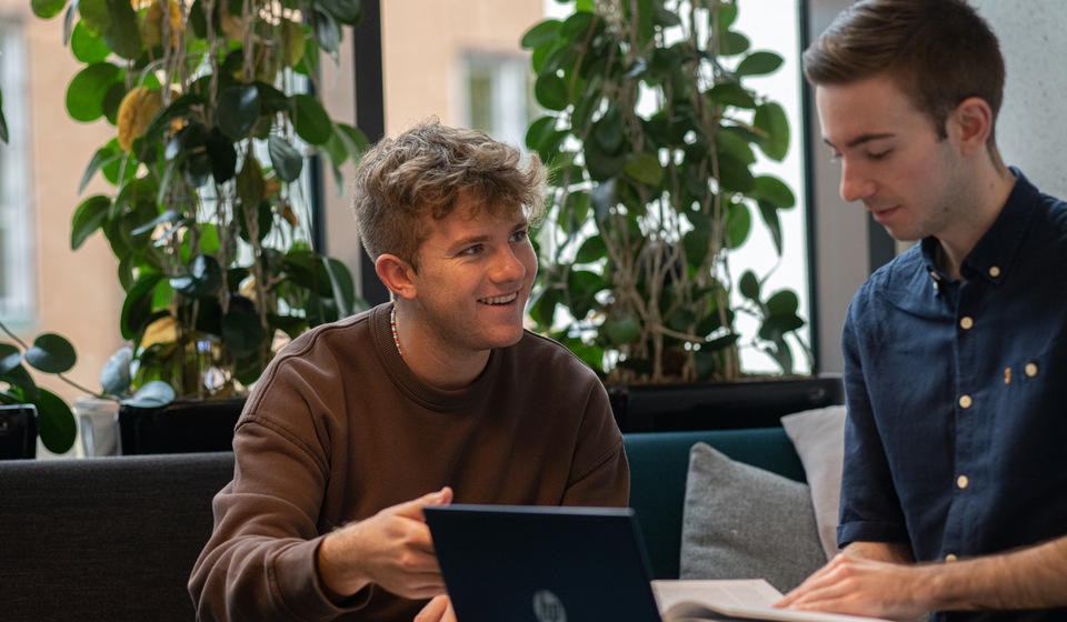 Studenter i samspråk vid laptop.