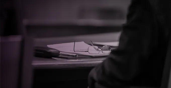 Glasögon på ett skrivbord, rosatonad bild.