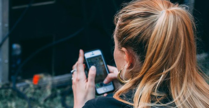 Kvinna bakifrån som håller i en mobiltelefon.