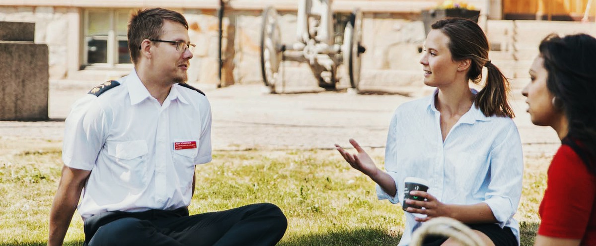 Officer and students sitting on a lawn outside the SEDU.