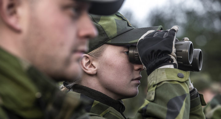 Två soldater betraktar något på avstånd, den kvinnliga soldaten kikar i kikare.