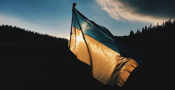Ukrainsk flagga mot bakgrund av skog.
