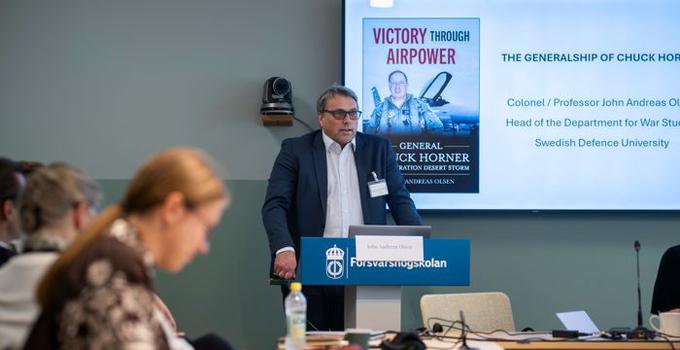 Man i talarstol i konferensrum.