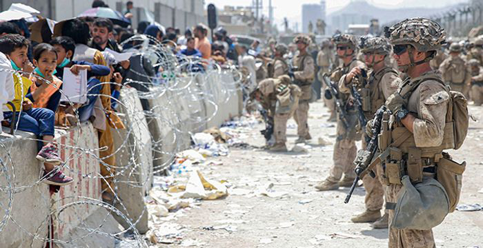 Vakter och människor bakom taggtråd.