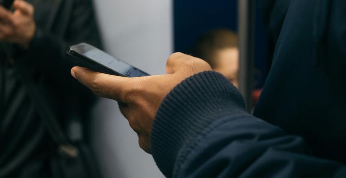 Hand som håller en mobiltelefon.