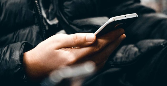 Närbild på en hand som håller i en mobil.