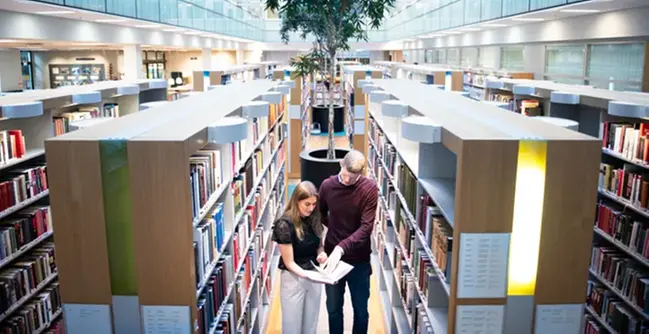Några personer som står i ett bibliotek.