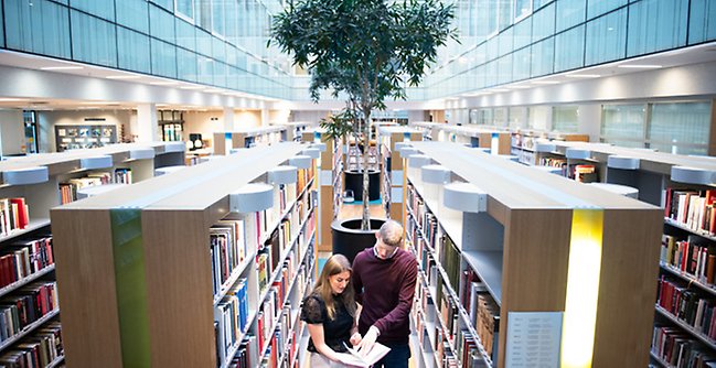 Några personer som står i ett bibliotek.