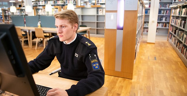 En man som sitter vid en dator på ett bibliotek.