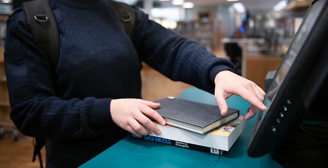 En kvinna som står vid en disk med en bok på den.