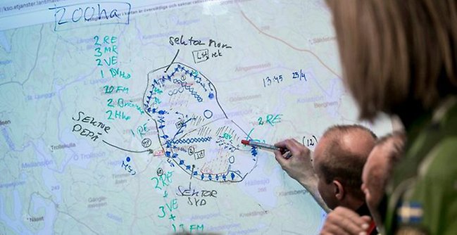 Personer som pekar på en whiteboard med en karta.