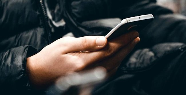 Närbild på hand som håller en mobiltelefon.