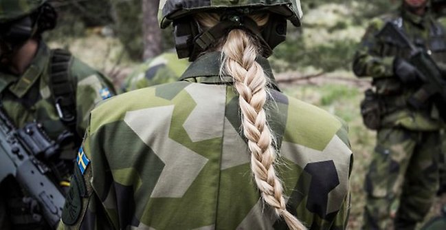Kvinnlig värnpliktig med fläta vänder ryggen till.