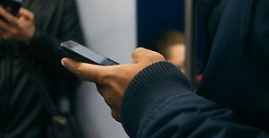 Hand som håller en mobiltelefon.