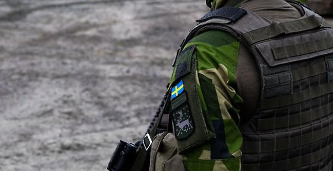 Man i kamouflageuniform sedd bakifrån.